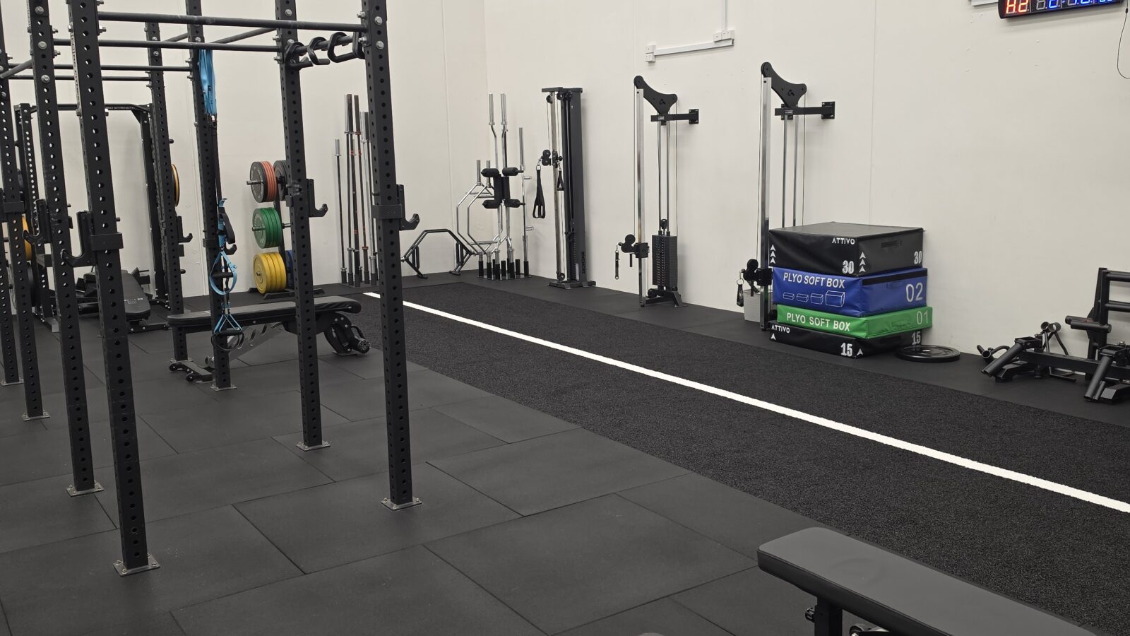 The rehabilitation gym at Adapt Sports Physiotherapy, with squat racks, barbells and a marked sprint lane.