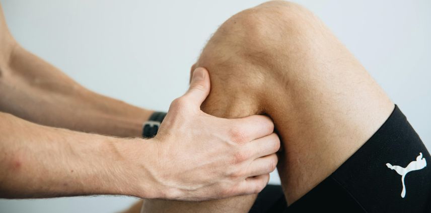 Physiotherapist assessing a patient's bent knee during a clinic consultation