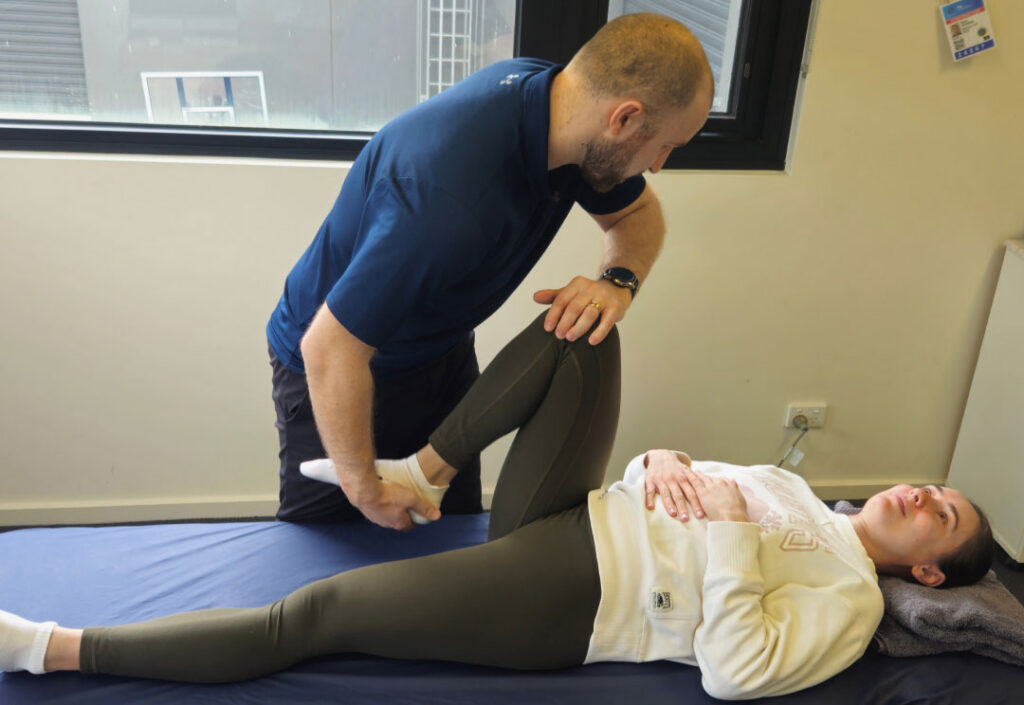 A physiotherapist assessing a client's knee during ACL treatment in the clinic.