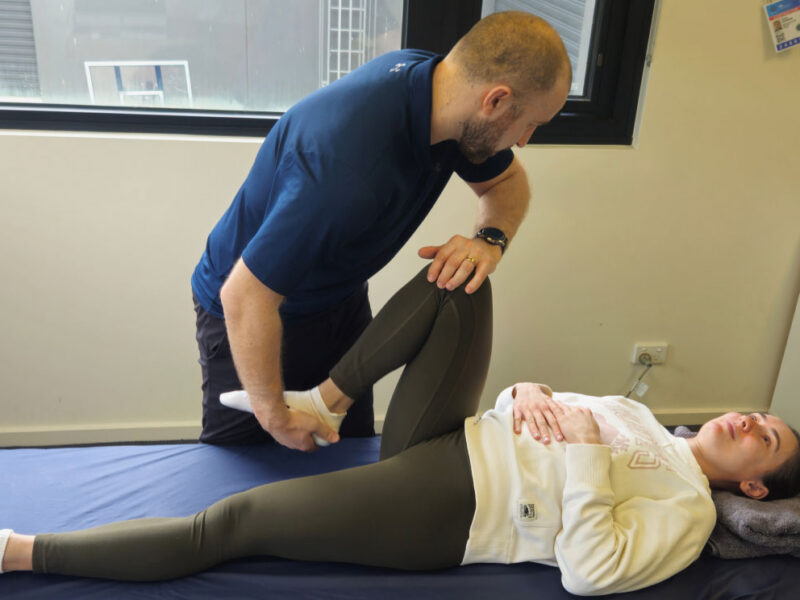 A physiotherapist assessing a client's knee during ACL treatment in the clinic.