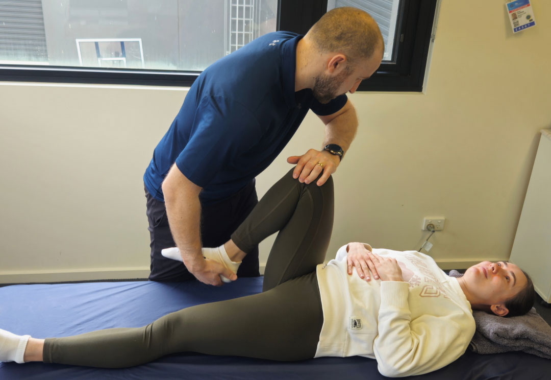 A physiotherapist assessing a client's knee during ACL treatment in the clinic.