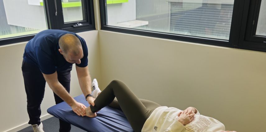 Physiotherapist holding and assessing a patient's ankle on the treatment table