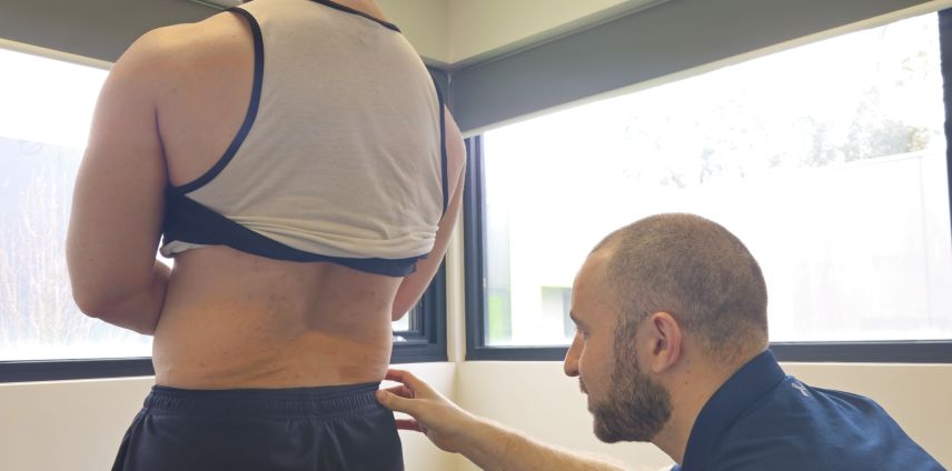 Physiotherapist palpating a patient's lower back during an assessment