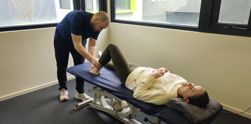 Physiotherapist stretching a patient's ankle on the treatment table