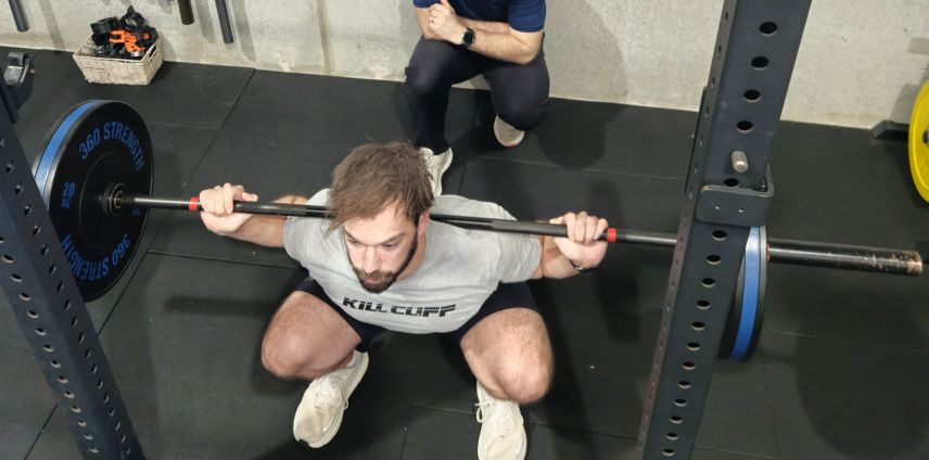 Physiotherapist observing an athlete performing a barbell back squat