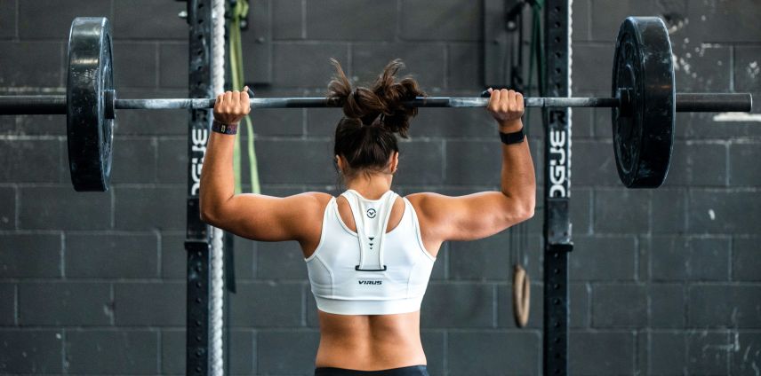 Athlete performing an overhead barbell press, showing shoulder and upper-back engagement