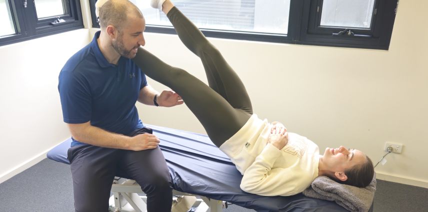 Physiotherapist assisting a patient with a straight-leg raise stretch