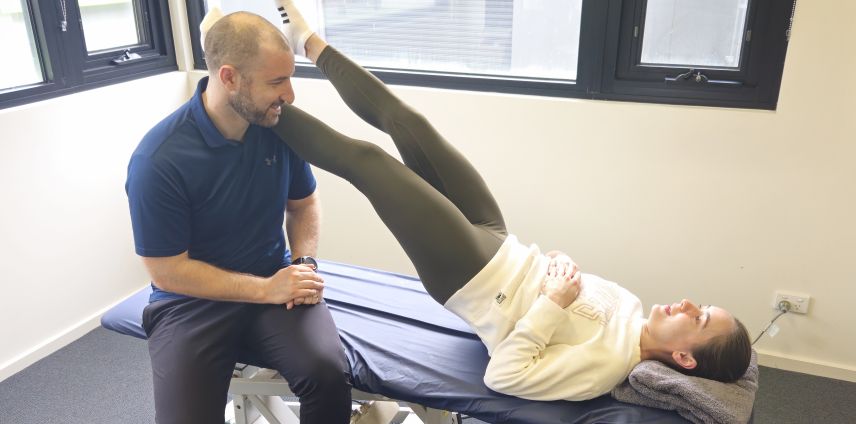 Physiotherapist assisting a patient with a straight-leg raise stretch