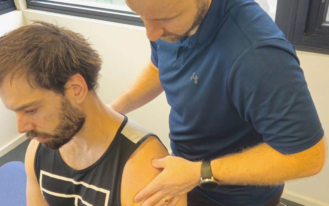 Physiotherapist assessing a patient's shoulder during hands-on treatment