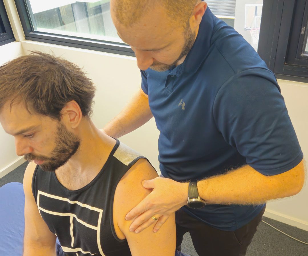 Physiotherapist assessing a patient's shoulder during hands-on treatment