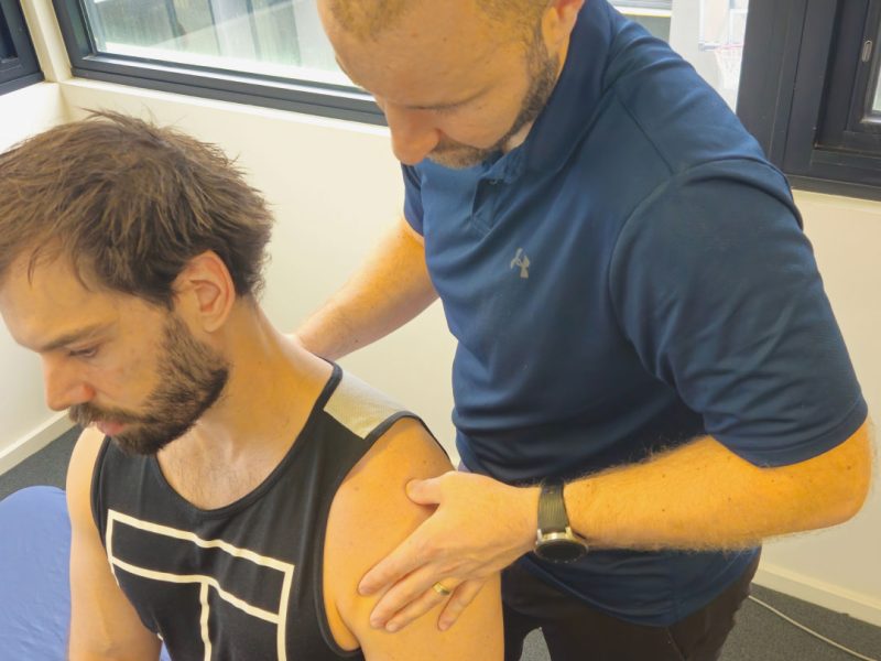 Physiotherapist assessing a patient's shoulder during hands-on treatment