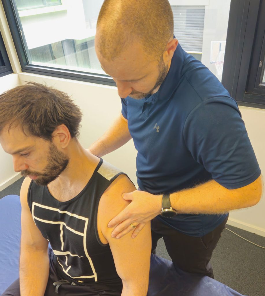 Physiotherapist assessing a patient's shoulder during hands-on treatment