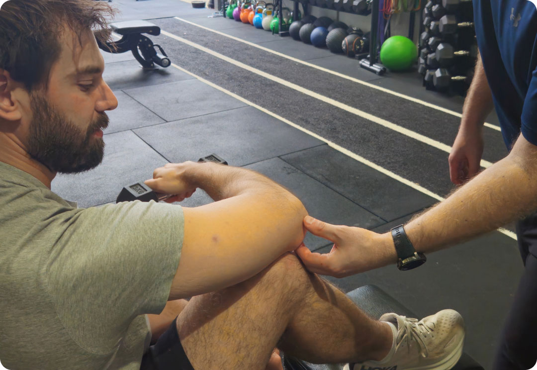 A physiotherapist assessing a client's knee during a gym-based session.
