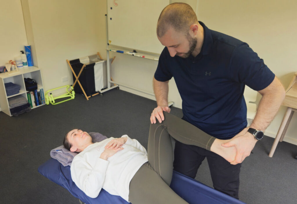 A physiotherapist examining a client's knee to assess the source of knee pain.