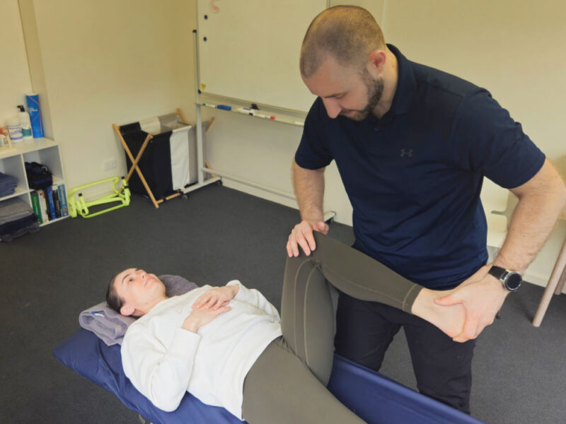 A physiotherapist examining a client's knee to assess the source of knee pain.