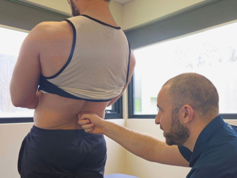 A physiotherapist identifying the source of a client's lower back pain during assessment.
