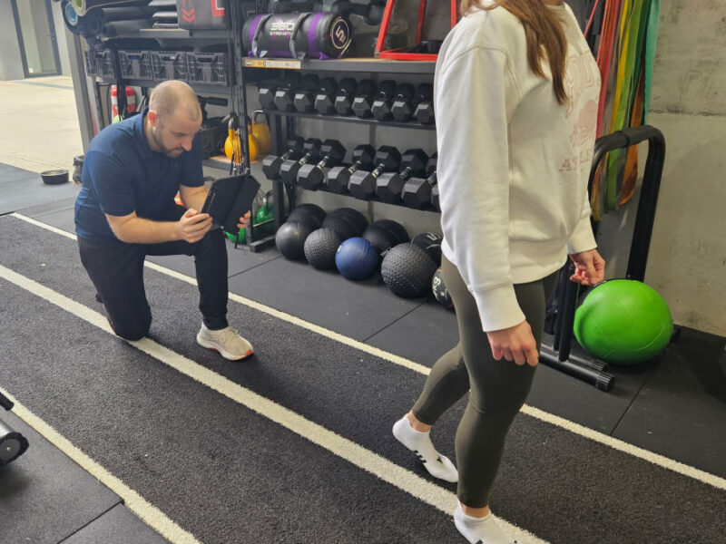 A physiotherapist analysing a client's ankle movement during assessment.