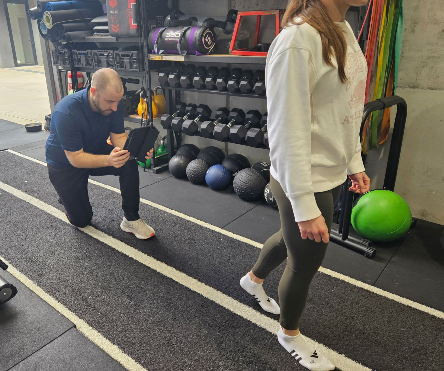 A physiotherapist analysing a client's ankle movement during assessment.