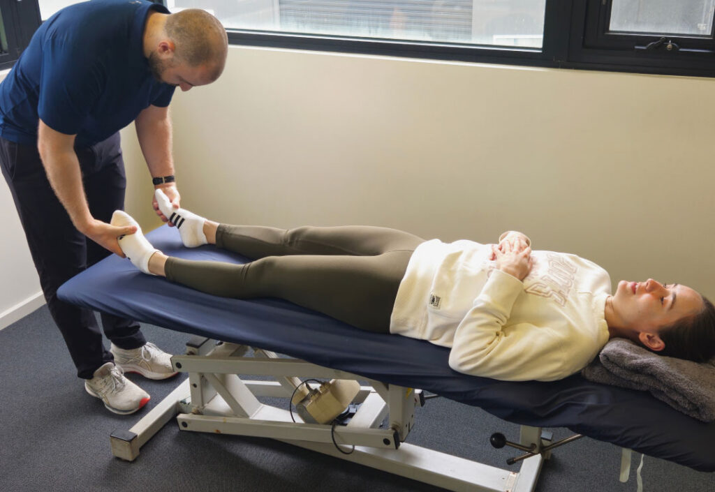 A physiotherapist examining a client's ankle for injury assessment.