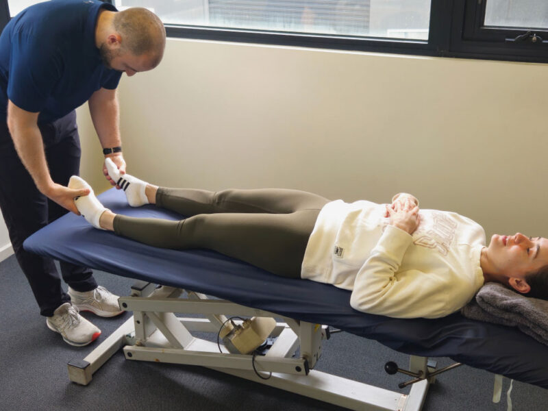 A physiotherapist examining a client's ankle for injury assessment.