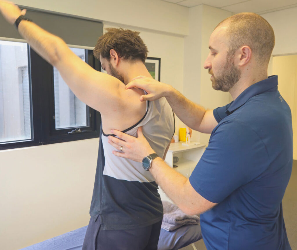 A physiotherapist examining a client's shoulder to assess shoulder pain.