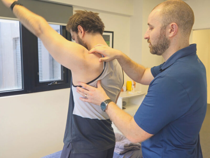A physiotherapist examining a client's shoulder to assess shoulder pain.