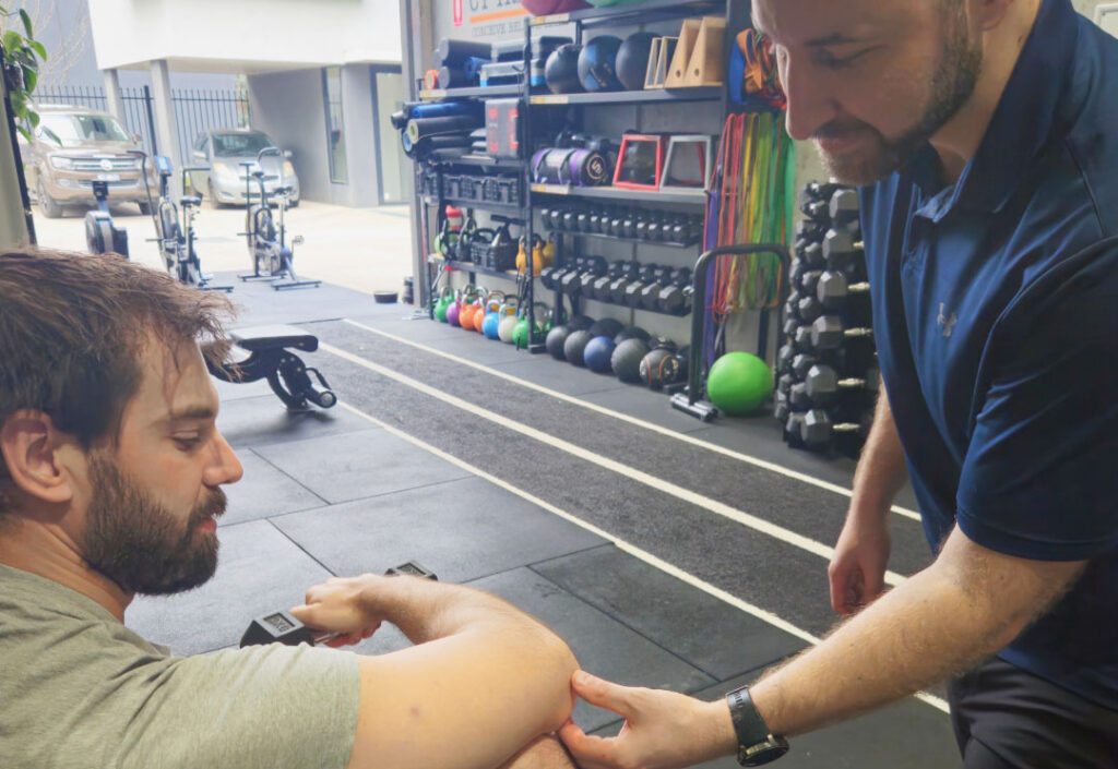 A physiotherapist examining a client's elbow to assess tennis elbow.
