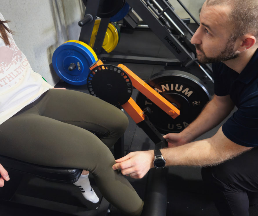 A physiotherapist guiding a client through gym-based rehabilitation exercises.