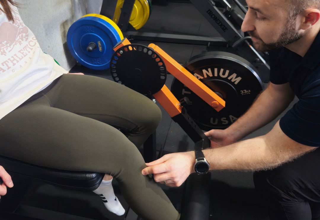 A physiotherapist inspecting a client's knee in the rehabilitation gym.