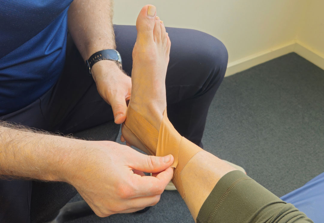 A physiotherapist taping a client's ankle in the clinic.