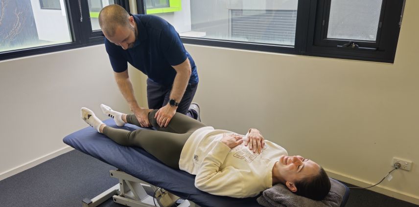 Physiotherapist performing a Lachman's test on a patient's knee to assess an ACL injury