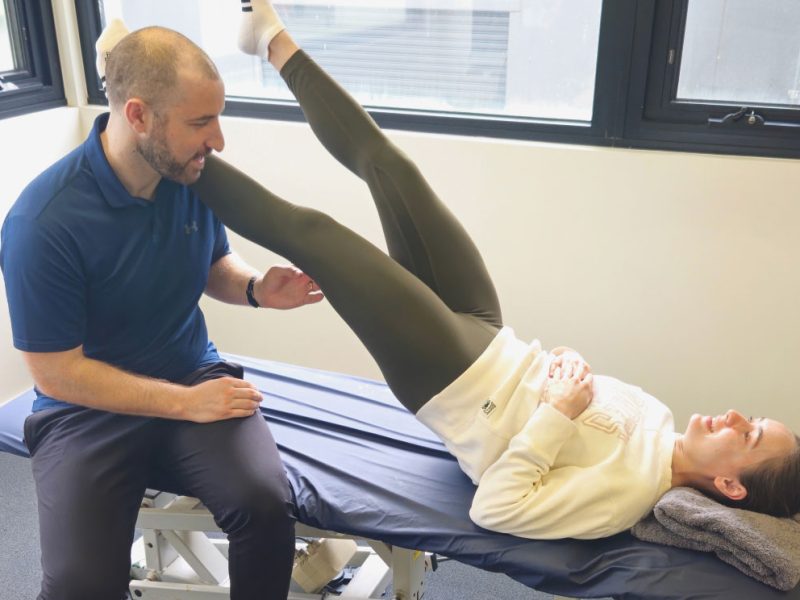 Physiotherapist assessing a runner's leg during a sports physiotherapy consultation