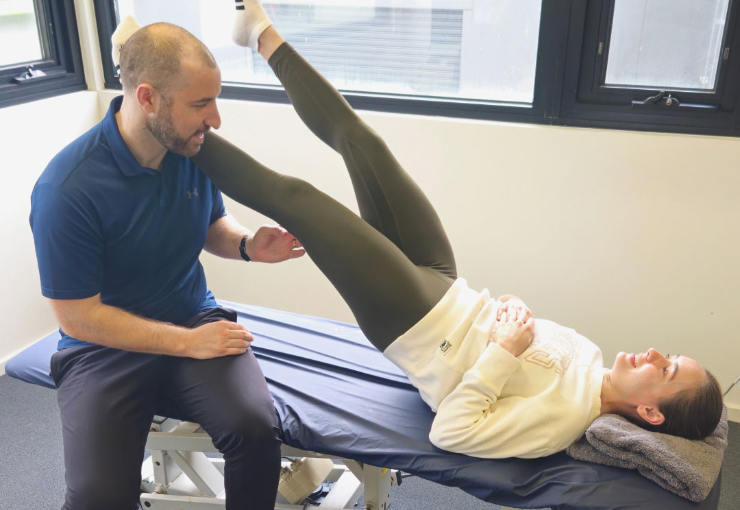Physiotherapist assessing a runner's leg during a sports physiotherapy consultation