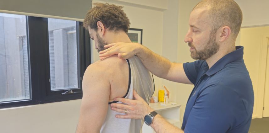 Physiotherapist assessing a patient's shoulder and upper back