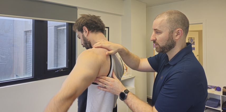 Physiotherapist assessing a patient's shoulder and upper back