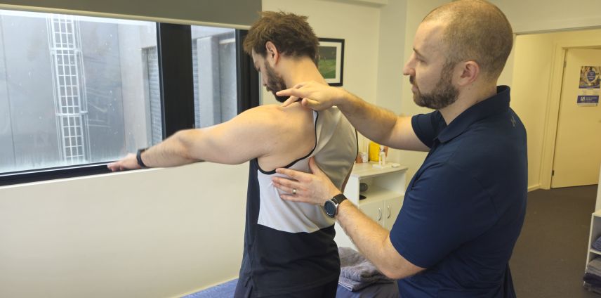 Physiotherapist assessing a patient's shoulder with the patient's arm extended