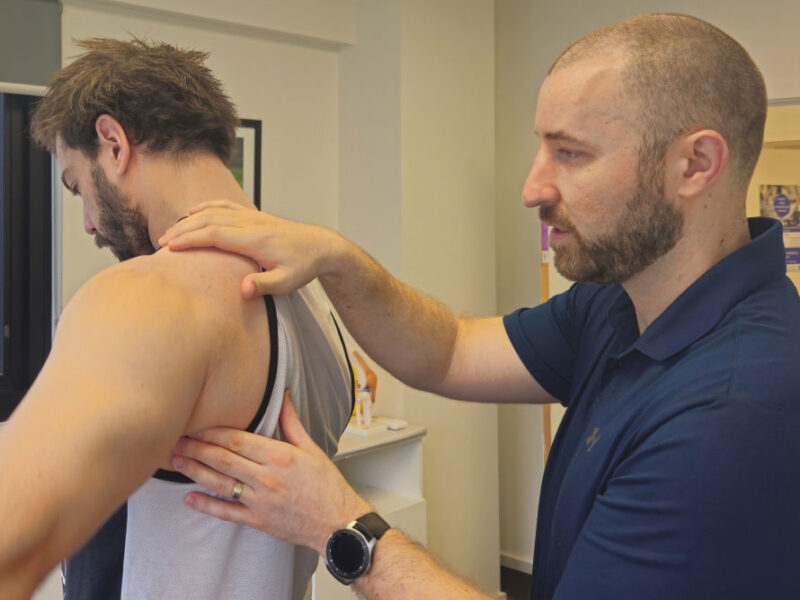 A physiotherapist examining a client's shoulder during a physiotherapy consultation.
