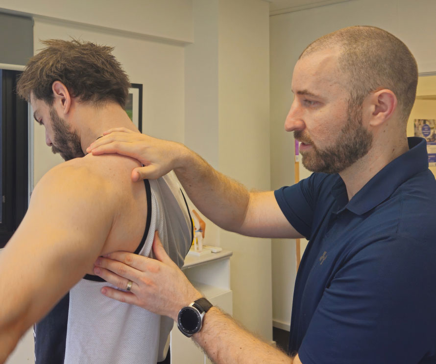 A physiotherapist examining a client's shoulder during a physiotherapy consultation.