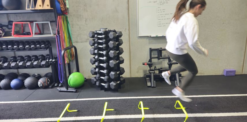 Woman jumping over agility hurdles during a training session