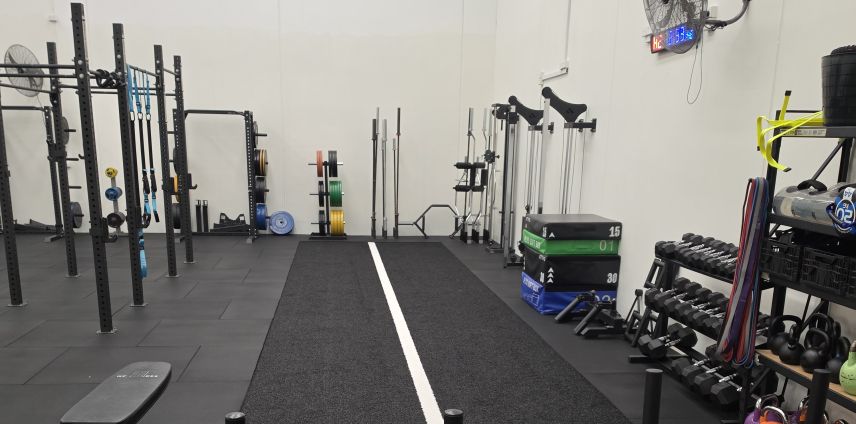 Empty gym training space with weight racks and equipment