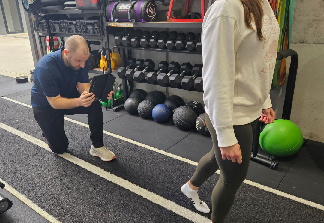 A sports physiotherapist analysing a client's injury during assessment.