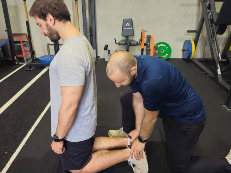 A physiotherapist guiding a client through gym-based rehabilitation.