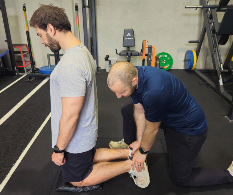 A physiotherapist guiding a client through gym-based rehabilitation.